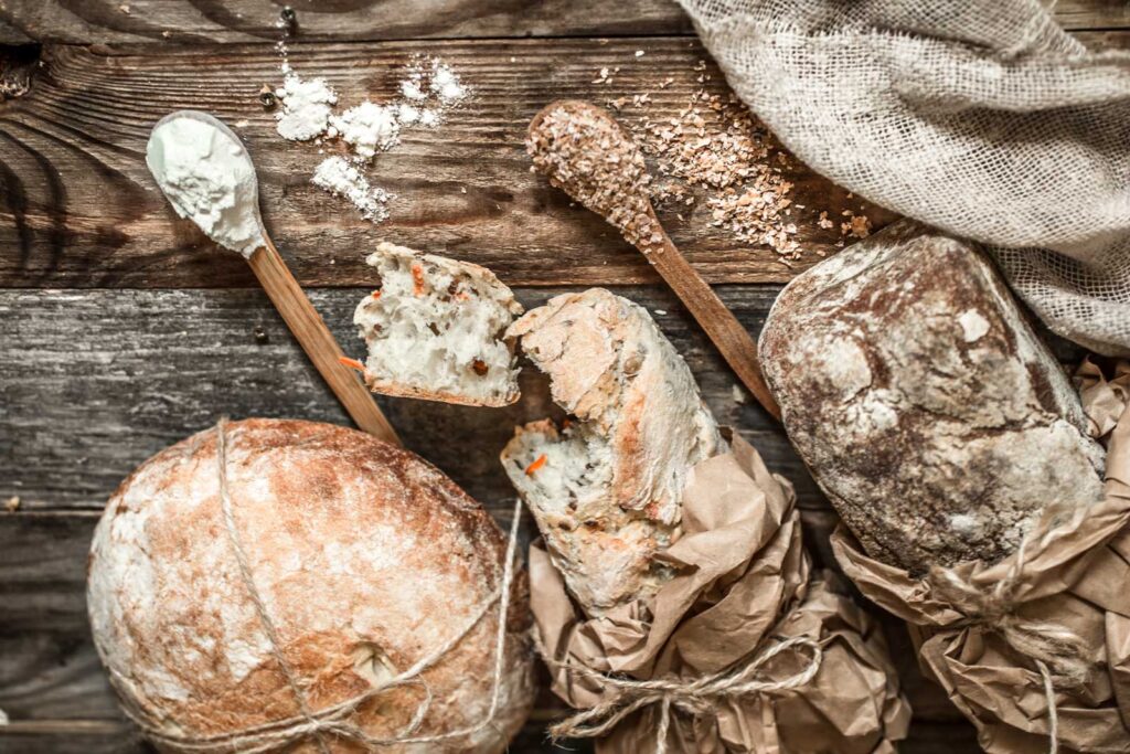 Pagnotte di pane fatte con lievitazione lenta, su un tavolo di legno.